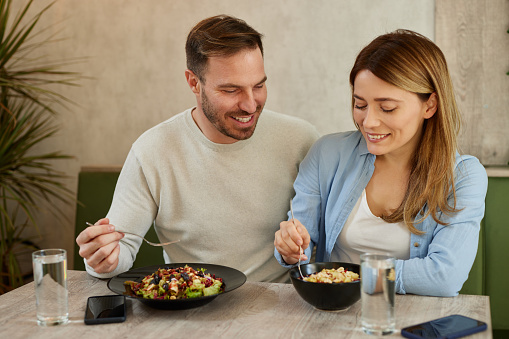 Mid adult couple enjoy eating salads in salad bar