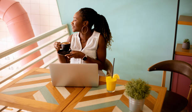 istock Young black woman drinking coffee  while working on laptop in the cafe 1477114675