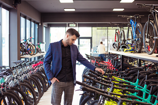 Young businessman watching bicycles in bicycle shop.