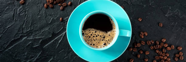 istock Blue coffee cup and coffee beans panorama, overhead flat lay shot on black 1477116268