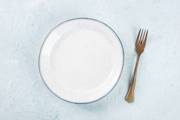 istock An empty white plate with a blue rim, with a fork, overhead flat lay shot 1477116354