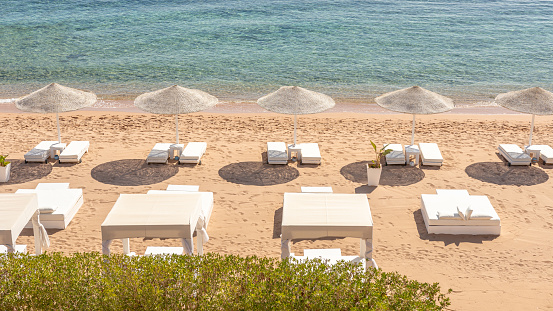 Chairs under umbrellas on tropical beach. Summer vacation concept.