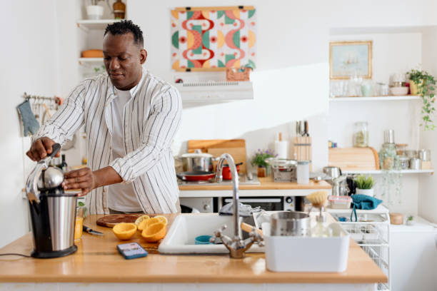 istock Man making fresh orange juice at the kitchen 1477119416