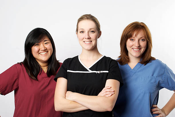 Happy Diverse Group of Medical Professionals Diverse Group of Medical Professionals looking at the camera on a white background red medical scrubs stock pictures, royalty-free photos & images