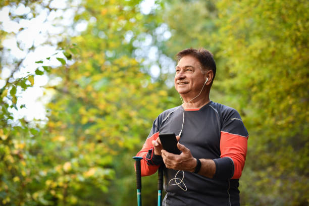 randonneur masculin senior souriant tout en documentant ses exploits dans la nature - pointer stick audio photos et images de collection