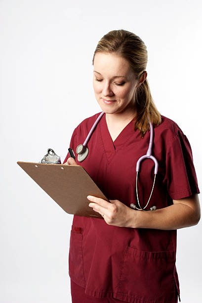 Medical Professional writing on Clip Board Medical Professional in red scrubs writing on a clip board red medical scrubs stock pictures, royalty-free photos & images