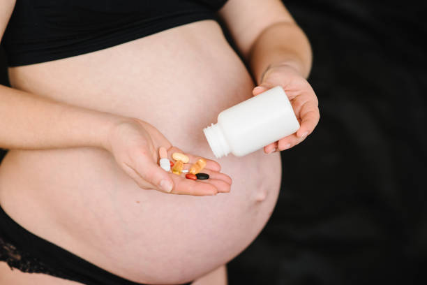 la mujer embarazada toma omega 3, multivitaminas, vitaminas b, c, d, tabletas de colágeno, probióticos, cápsula de hierro. la niña tiene vitaminas diariamente. foto en primer plano de manos femeninas sosteniendo suplementos con una botella blanca. - vitamina b 3 fotografías e imágenes de stock