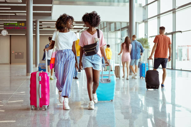 podróżni spacerujący z bagażem na lotnisku - airport tourist airport lounge young men zdjęcia i obrazy z banku zdjęć