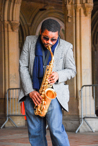 Central Park, New York City - USA: Close-up of Afro-American musician playing his saxophone under Bethesda Terrace Arcade, Central Park, NYC. Pillars of archway serve as backdrop.