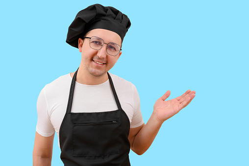 Happy smiling chef looking at camera on blue background. The concept of cooking.