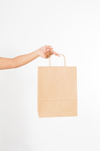 Template blank package. African american woman hand holding a paper kraft bag isolated on white background. Delivery and shopping concept.