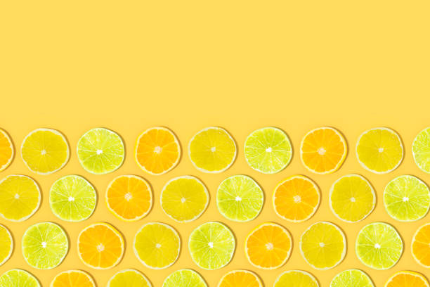istock Lime and Orange Fruit Slices with Sunlight on Yellow Color Background 1477146120