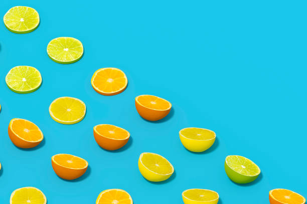 istock Lime and Orange Fruit Slices with Sunlight on Blue Color Background 1477147046