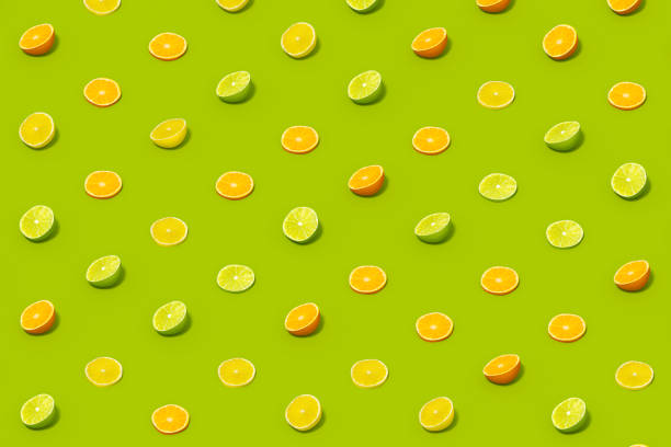 istock Lime and Orange Fruit Slices with Sunlight on Green Color Background 1477147151