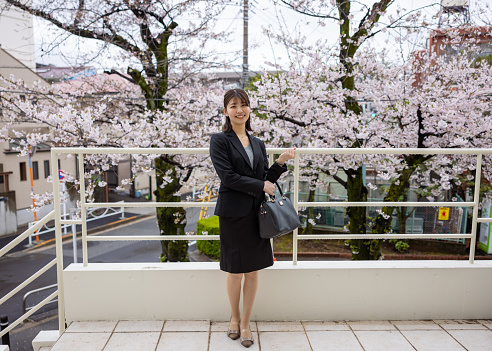 Full Length portrait of young business woman standing in front of cherry blossoms