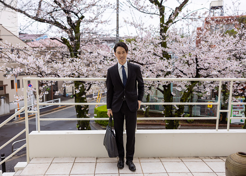 Full length portrait of businessman standing in front of cherry blossoms
