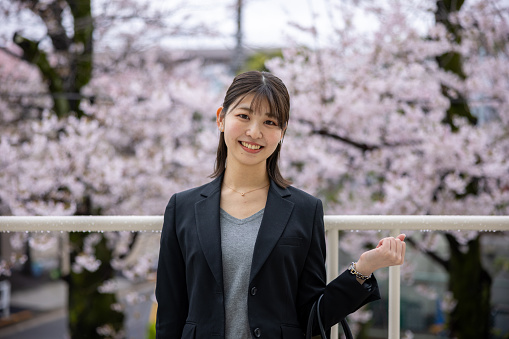 Portrait of young business woman standing in front of cherry blossoms