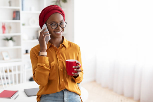 istock Happy young black woman talking on phone, having coffee break 1477153109