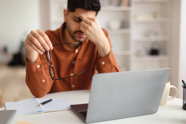 Bored Asian male worker sitting at desk with pc