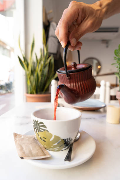 istock Waiter pouring red tea in a cup by a cast iron teapot 1477155406