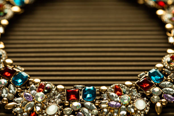 Closeup view of multi-colored crystal necklace on a brown textured background, with copy space
