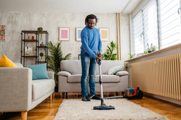 istock Young Man Vacuuming The Carpet In His Apartment 1477155976