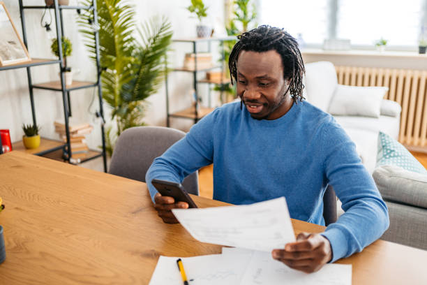 istock Young Man Checking His Finances On The Phone At Home 1477156373