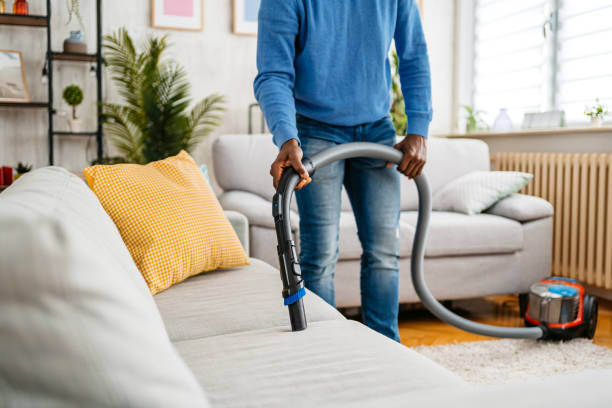 istock Young Man Vacuuming The Sofa In His Apartment 1477156430