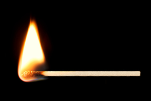 Horizontal burning match isolated on black background.