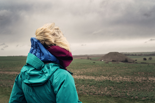 Rear view of a lonely woman looking out over a bleak moorland.