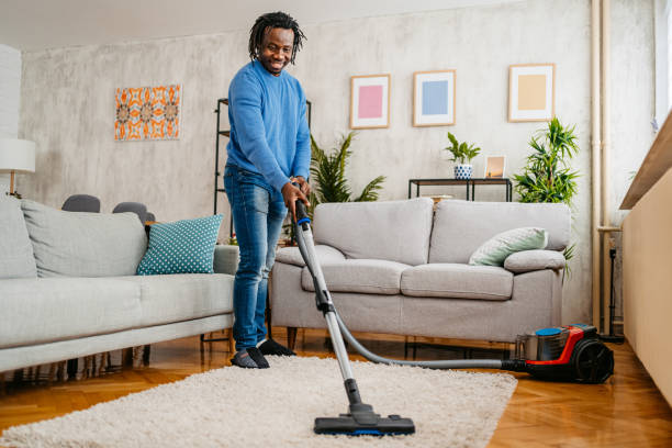 istock Young Man Vacuuming The Carpet In His Apartment 1477164001