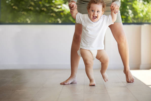 neonato, imparare e camminare con la mamma in supporto, primi passi e sviluppo corporeo sano per i bambini. madre che si tiene per mano nell'insegnamento eccitata, sorridente e felice bambino piccolo equilibrio, cura e crescita - steps baby standing walking foto e immagini stock