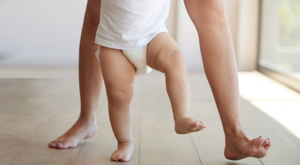 istock Baby, learning and walking with a child taking its first steps with his mother to learn to walk at home. Feet, legs and balance with a kid stepping forward for growth and development in the house 1477166462