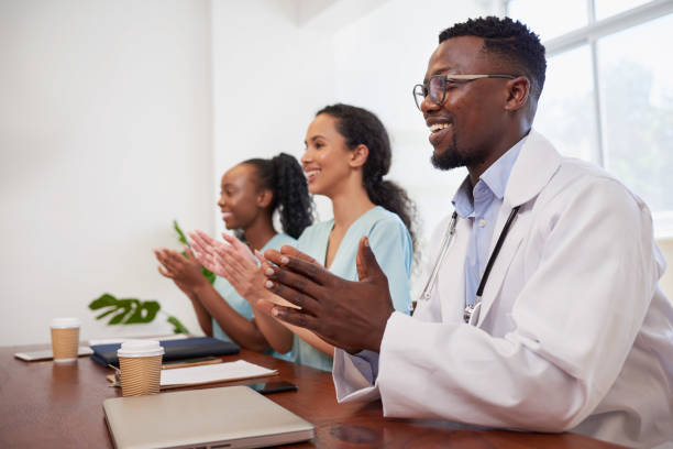 istock Three doctors in a row, clapping at medical presentation in hospital boardroom 1477173100