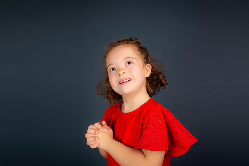 Beautiful and happy girl making gestures with both hands. Isolated on gray background.