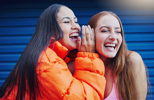 Gossip, women talking and friends, laughing and reunion, bonding and blue wall background. Ladies, happy females and girls outdoor, quality time and conversation for funny, silly story and carefree