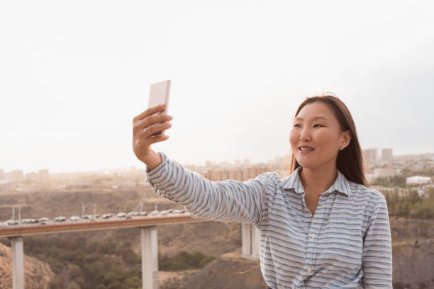istock Young asian woman doing selfie using phone outdoors 1477179822