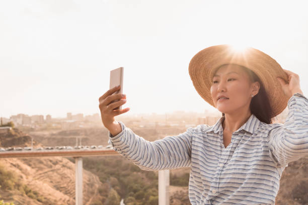 istock Young asian woman in hat doing selfie using phone outdoors 1477179834