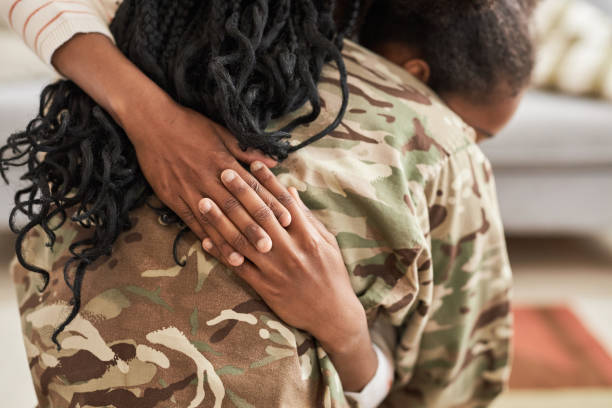 Close-up of military mom in uniform embracing her little child before she leving for service