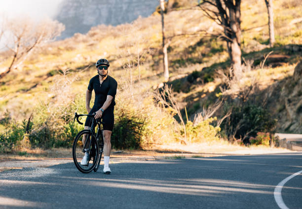 istock Young male cyclist relaxing during training on an empty road in wild terrain 1477181183