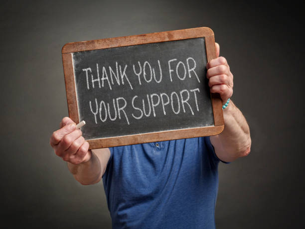 istock thank you for your support - white chalk writing on a slate blackboard held by a men 1477181653