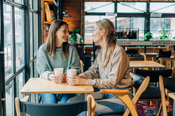 istock Two female friends are chatting and drinking coffee while sitting in a coffee shop. 1477183256