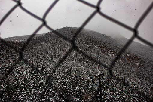 This shot was taken near Manitou Springs, Co. The mountain pictured here is near the Manitou Incline. This was a beautiful foggy snowy day and looking at the mountain through the chain link fence gives more depth to the image.