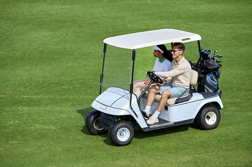 Asian Chinese golfers driving golf cart in golf course weekend morning playing golf