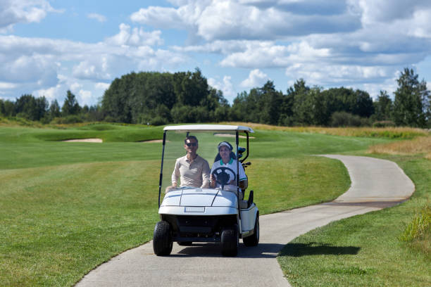 istock Couple driving golf cart across golf club fields 1477183548