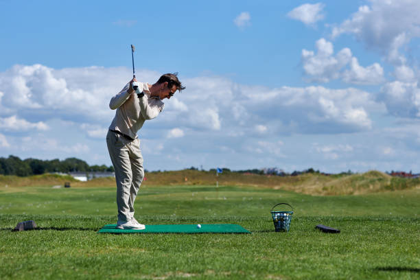 istock Side view man playing golf on green grass and swinging golf club 1477183569
