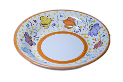 one white empty ceramic plate with a color pattern and blue border stands on a brown table