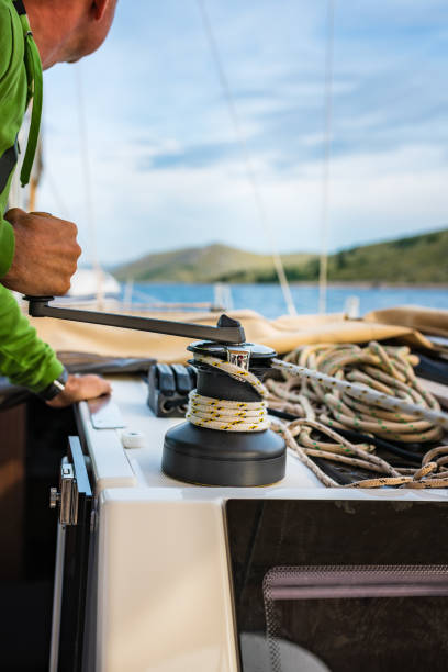 istock Sailor winding rope of foresail with rotating handle on winch 1477184848