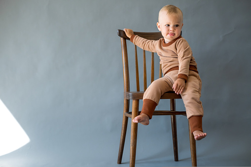 Portrait cute one year old baby girl, sitting on a wooden chair