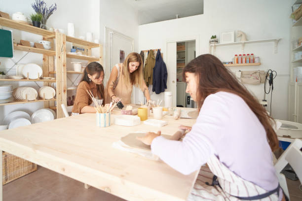 istock Friends with aprons in a pottery workshop preparing clay to create pieces. Crafts class. 1477185321